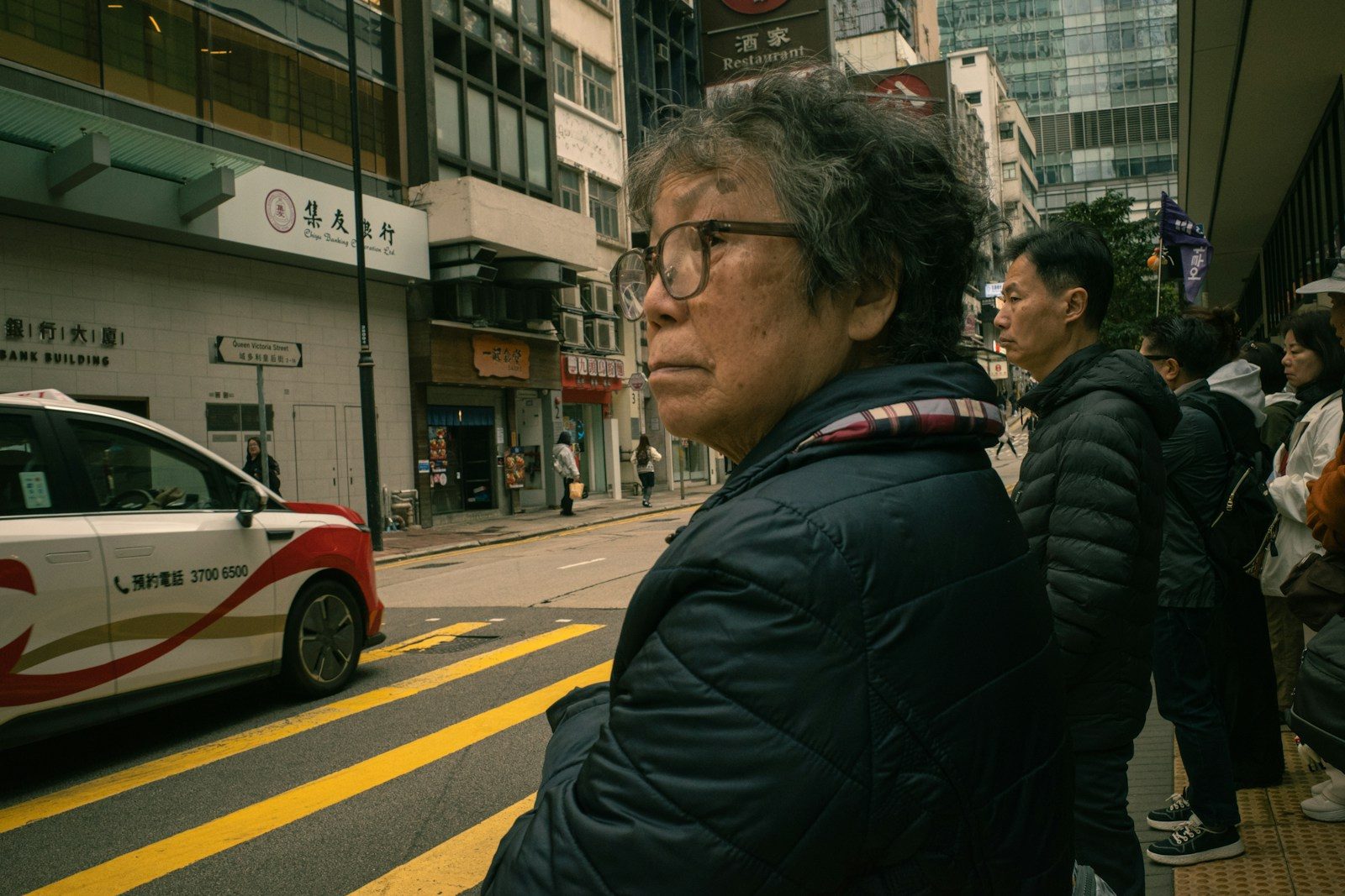 Elderly woman waiting at a city crosswalk