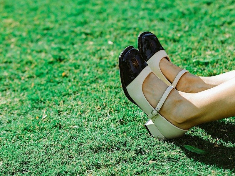 Feet in two-toned shoes resting on vibrant green grass