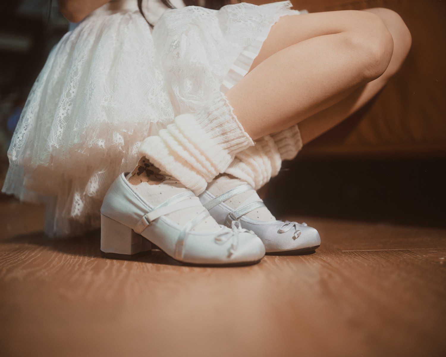 Woman in white dress, socks, and shoes crouching
