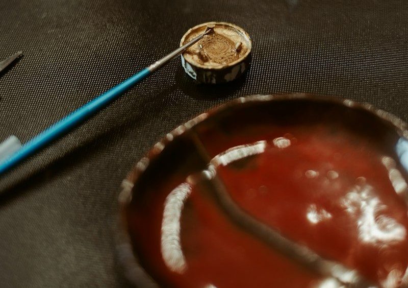 Paintbrush in a container near a painted bowl